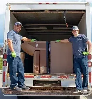 Two Happy Panda Junk Removal crew members loading furniture into the truck in Calgary