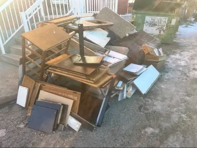 Tables, desks and cabinet doors stacked in an alley ready for loading