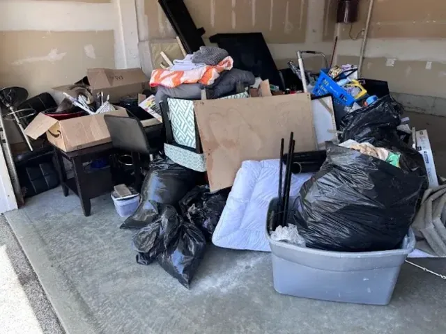 Before: Household clear-out: bags, a mattress and furniture taken from a single garage